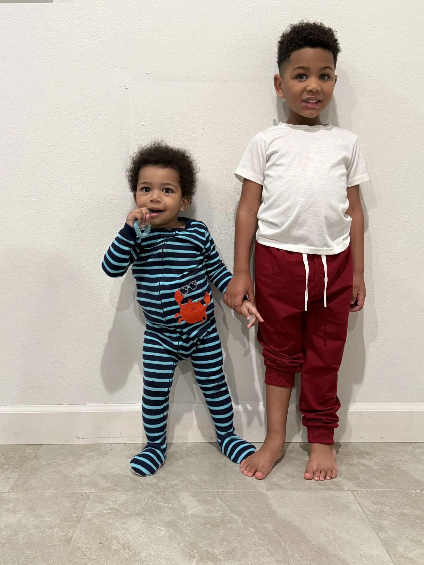 Yande and Luis, holding hands against a white wall